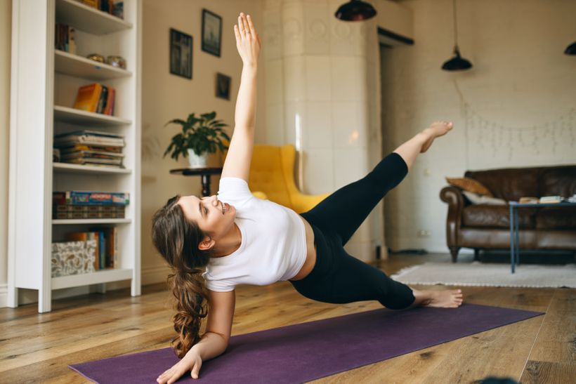 Žena cvičící side plank doma ke zlepšení zpevněného břicha.