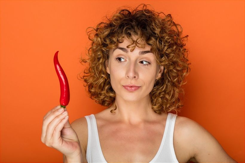 Žena držící pálivou chilli papričku k snězení a zrychlení metabolismu