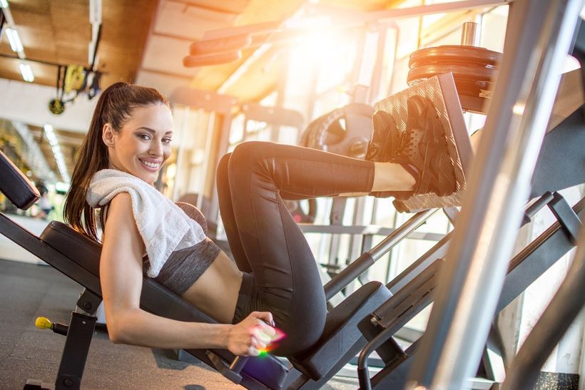 Športujúca žena spaľuje kalórie v posilňovni na leg press stroji